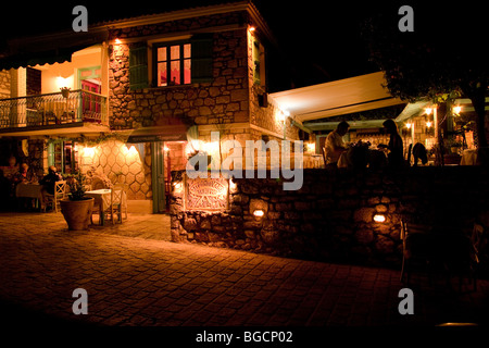 Two couples silhouetted, seated at tables having an evening dinner in a romantic Stromboli taverna, Afitos, Greece Stock Photo