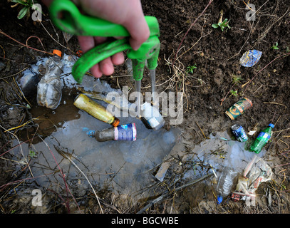 A refuse collector using a grabber to clean litter from a ditch Stock Photo