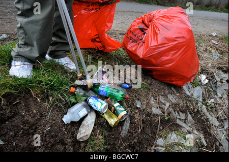 A refuse collector using a grabber to clean litter from a roadside ditch Stock Photo