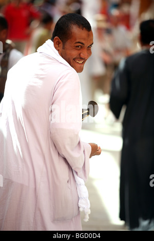 Egyptian salesman looking over his shoulder and smiling at the Valley of the Kings tourist area in Egypt Stock Photo
