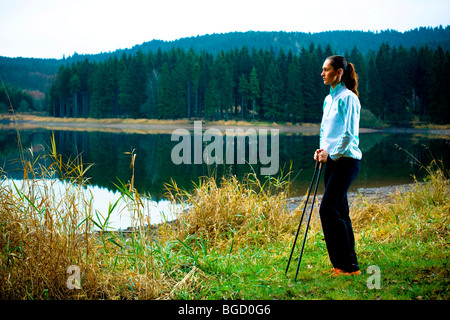 Young woman doing nordic walking beside a lake Stock Photo