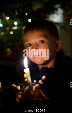 Young boy holding a Christingle at a carol service on Christmas Eve Stock Photo