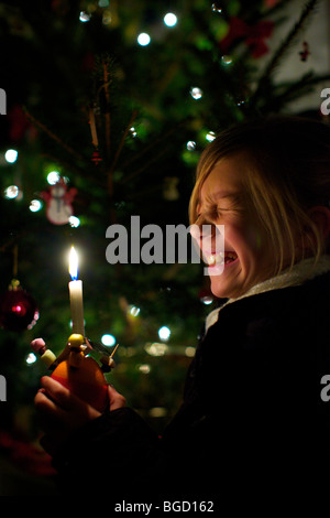 Young girl holding a Christingle at a Carol service at Christmas Stock Photo