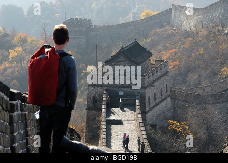 Young man with a red backpack, Great Wall of China with visitors at the tower at Mutianyu in the fall, near Beijing, China, Asia Stock Photo