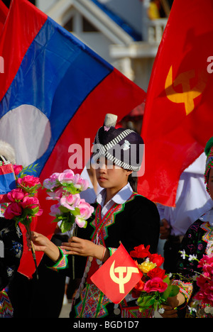 Festival, Hmong girl, dressed in traditional clothing, holding red flags of the Communist Party, national flag of Laos, Xam Neu Stock Photo