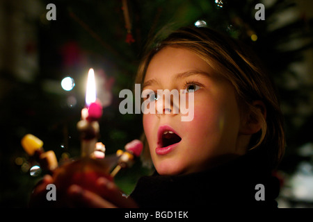 Young girl holding a Christingle at a Carol service at Christmas Stock Photo