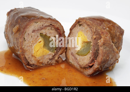 Stuffed beef roulade with gravy, cut in half, filled with minced meat, gherkin, onion and egg Stock Photo