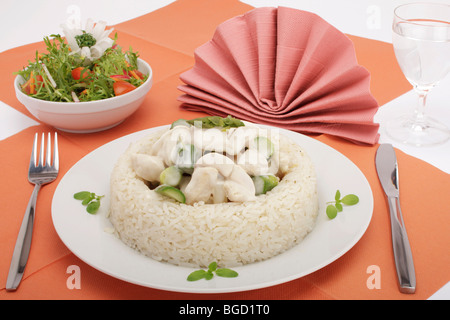 Chicken fricassee with mushrooms and green asparagus surrounded by a rice border, mixed salad Stock Photo