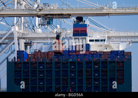 Container crane lifting portainer shipping container from cargo ship ...