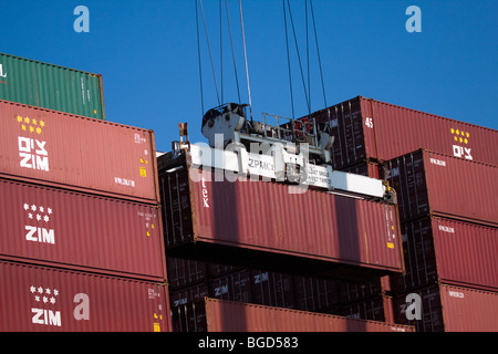 Closeup of crane lifting shipping portainer off of cargo container ship ...