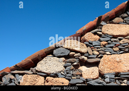 Various types of volcanic stone used in the building of an exterior house wall and hand made roof tiles in the old village Stock Photo