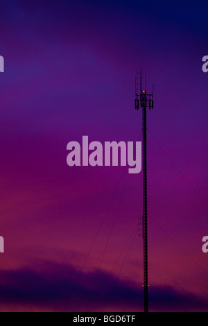 A communication tower is silhouetted against a colorfull sunset in Rouyn-Norenda in Abitibi Stock Photo