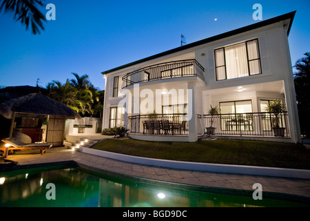 Luxurious mansion exterior at dusk overlooking pool Stock Photo