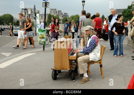 Tourists and Street Musician Playing a Piano, Pianist or Piano Player, Pont de l'Archevèche, Île de la Cité, Paris, France Stock Photo