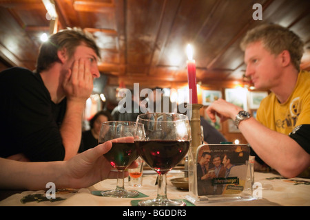 Young people sat drinking wine around a table in an apres ski bar. Modern lifestyle. St Anton, Austria, Europe. Stock Photo