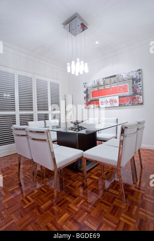 Luxury home dining room interior with dark brown wooden flooring and white leather dining furniture Stock Photo