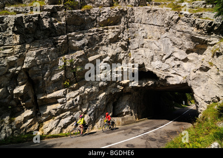 Cyclists in front of rock arch, L'Auberson, Canton Vaud, Switzerland, Europe Stock Photo