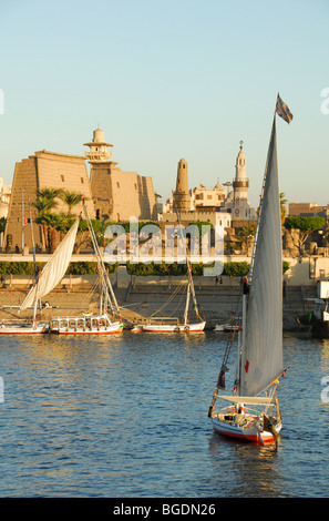 LUXOR, EGYPT. A sunset view of a felucca on the River Nile, with the Corniche and Luxor Temple behind. 2009. Stock Photo