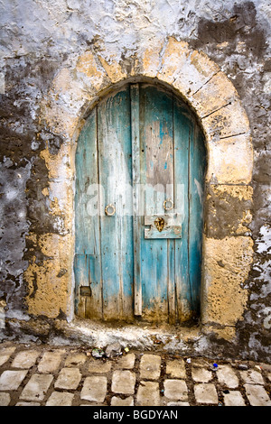 Old arched door in a wall from a cobbled courtyard in Tunisia Stock Photo