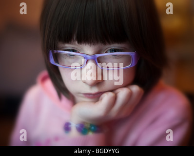 9 year old girl concentrates on computer screen Stock Photo