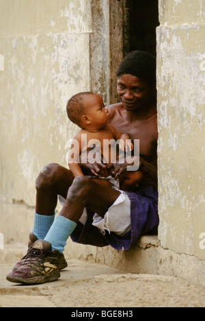 A resident in a leper colony in Luanda, Angola, holds his young son. Stock Photo
