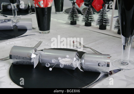 Christmas dinner decorations including a silver christmas cracker on a modern/trendy dining table Stock Photo