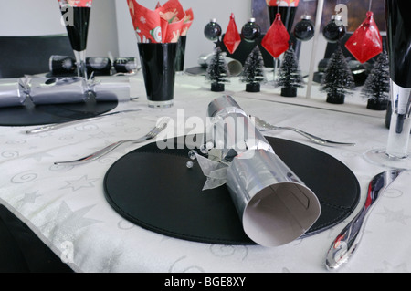 Christmas dinner decorations including a silver christmas cracker on a modern/trendy dining table Stock Photo