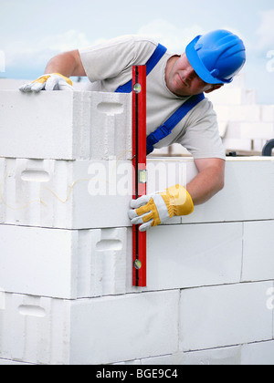 Mason checking plumb line of house wall being made from aerated autoclaved concrete blocks Stock Photo