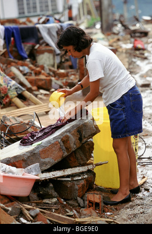 The 1999 earthquake in Colombia was the strongest to strike Colombia for 16 years. a woman washes a shirt on a broken wall. Stock Photo