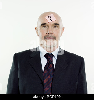 studio portrait isolated on white background of a man senior having a post-it with a question mark on his head Stock Photo