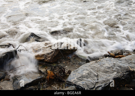 surf breaking over rocks on a beach Stock Photo