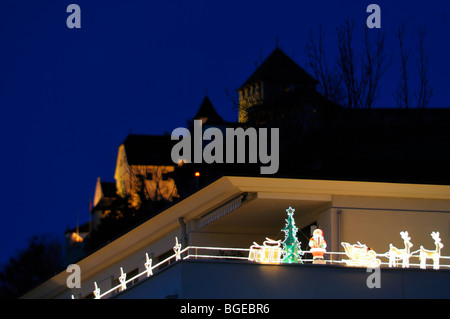Santa Claus Sledge with two Reindeer and a green Christmas Tree decoration in front of the princely castle at nightfall, Vaduz LI Stock Photo