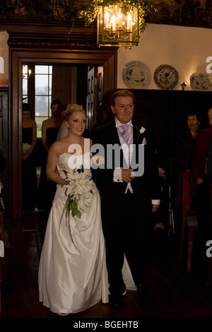 A father proudly leads his bride daughter down the aisle in a civil wedding at a licensed ceremony in Essex, England. Stock Photo