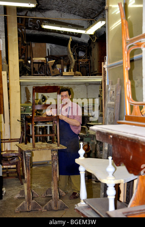 Craftsman works on a chair in a furniture repair shop, Rome, Italy Stock Photo