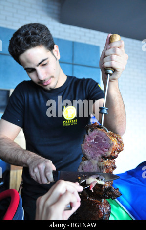 Carving Argentinian style grilled meat off a skewer Stock Photo