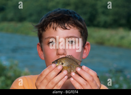 8 year-old boy holding a Pumpkinseed Sunfish (Lepomis gibbosus) at the Watershed Pond. Pennington, New Jersey Stock Photo