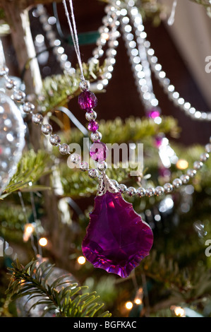 A glass pink bauble hangs on a Christmas tree with other collections of colourful decorations as Christmas. Stock Photo