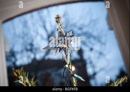 A festive star is placed on top of a Christmas tree in a bay window of a living room. Stock Photo