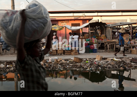Street scene in Gonaives, Artibonite Department, Haiti, showing an incomplete drainage canal filled with rubbish. Stock Photo