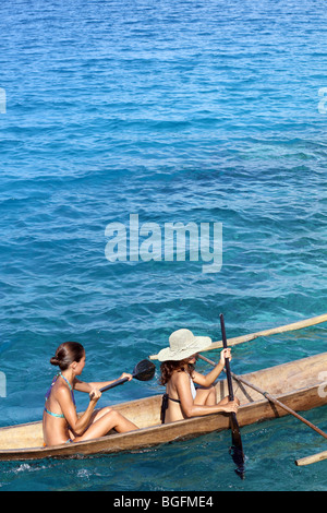 Two young woman paddling an outrigger canoe at Simakakang Island in the Mentawai Islands Stock Photo