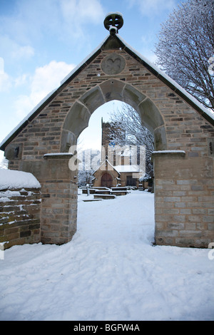 Church in England with tower visible through the entrance arch on a bright sunny day with winter snow on the ground Stock Photo