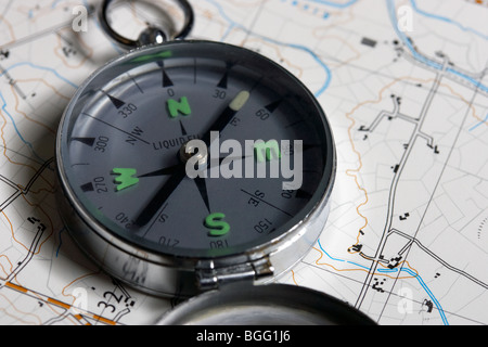 old style liquid filled metal compass resting on a map Stock Photo