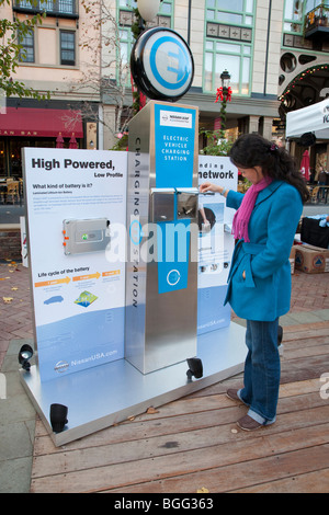Woman looking at promotional display about the electric vehicle charging stations network infrastructure. Stock Photo