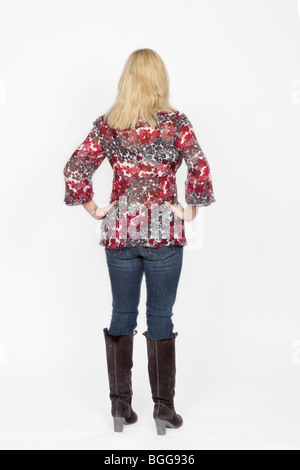 Blonde woman standing with back to camera, hands on hips Stock Photo