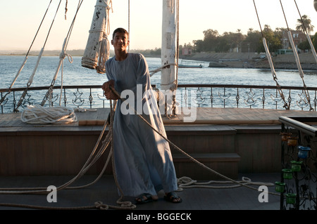 Young man sails a boat down the Nile River at sunset. Stock Photo