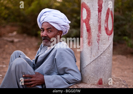 Turbaned Egyptian man sitting on the side of a road along the Nile River. Stock Photo