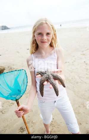 Girl holding a starfish into the camera Stock Photo