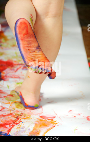 Stock photo of a 3 year old girl enjoying some creative play with feet paints. Stock Photo