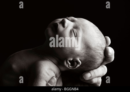 Beautiful Low Key Shot of a Father's Hand Holding a New Born Child Stock Photo