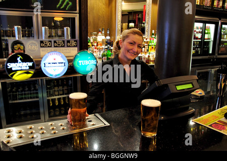 Barmaid working behind bar, The King & Castle Pub, Thames Street, Windsor, Berkshire, England, United Kingdom Stock Photo
